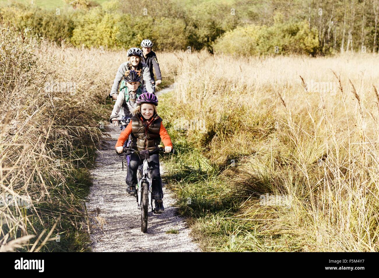 Vorderansicht der Familie Radfahren auf ländlichen Weg Blick auf die Kamera zu Lächeln Stockfoto