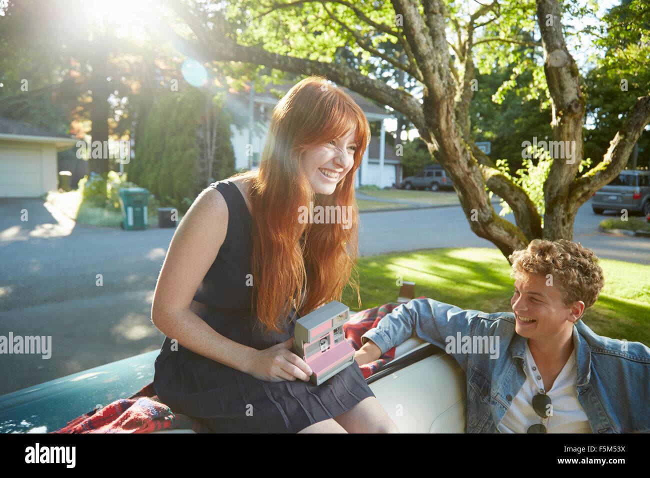 Junges Paar mit Oldtimer Cabrio mit Sofortbild-Kamera Stockfoto