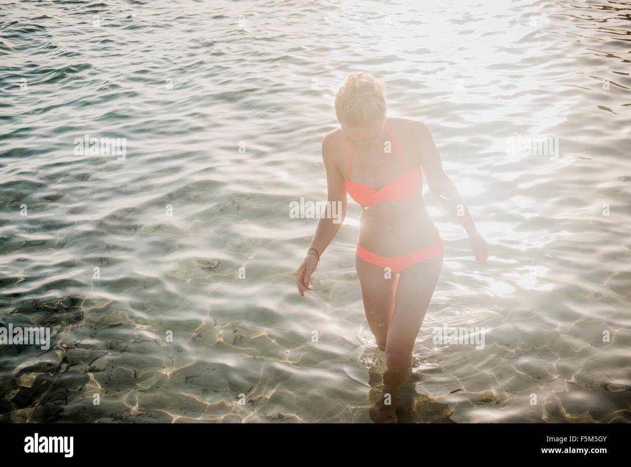 Mitte erwachsenen Frau trägt Bikini Paddeln im sonnigen Meer Stockfoto
