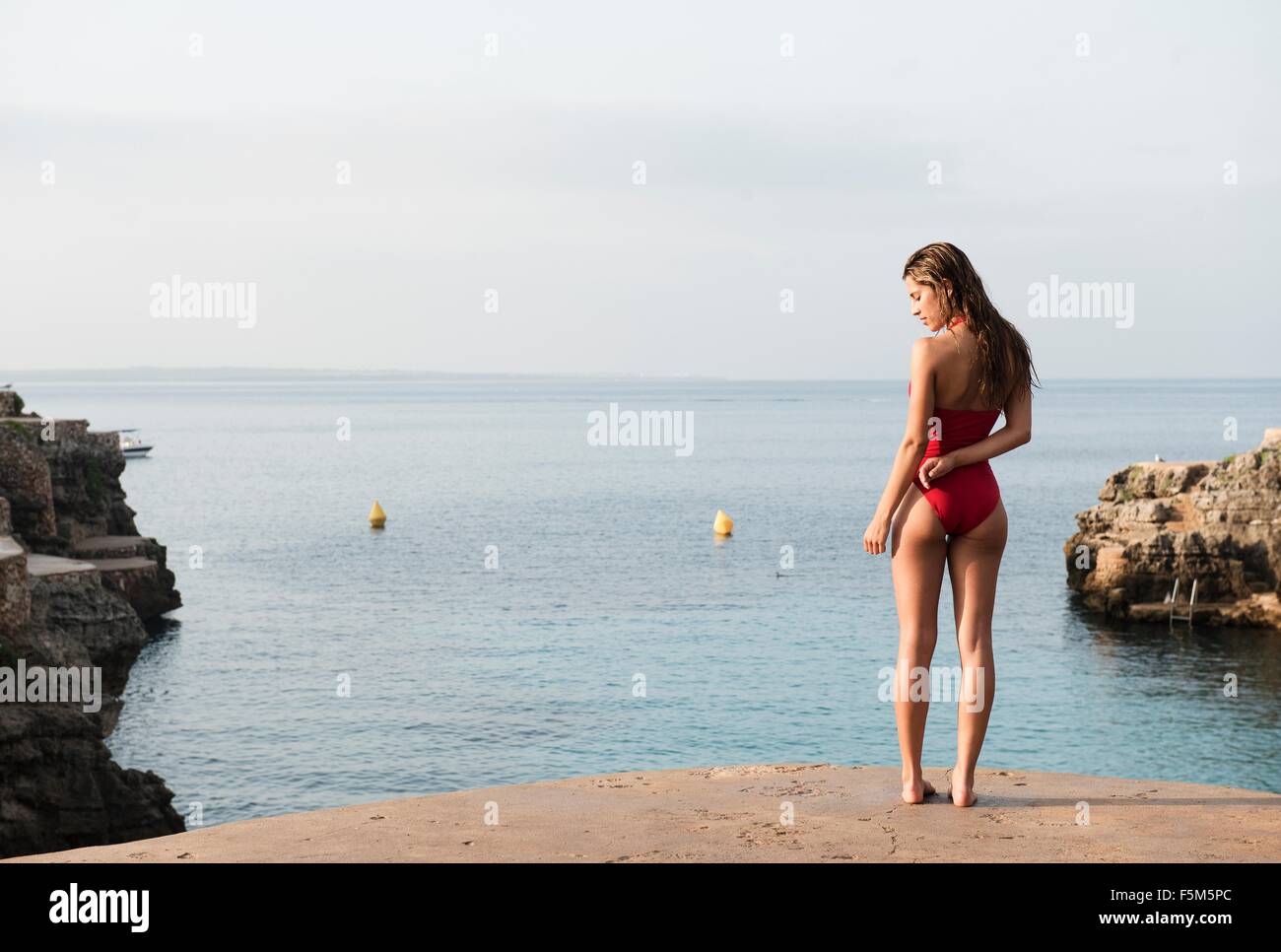 Rückansicht des jungen Frau im Badeanzug blickte von Cala de Brut, Menorca, Balearen, Spanien Stockfoto