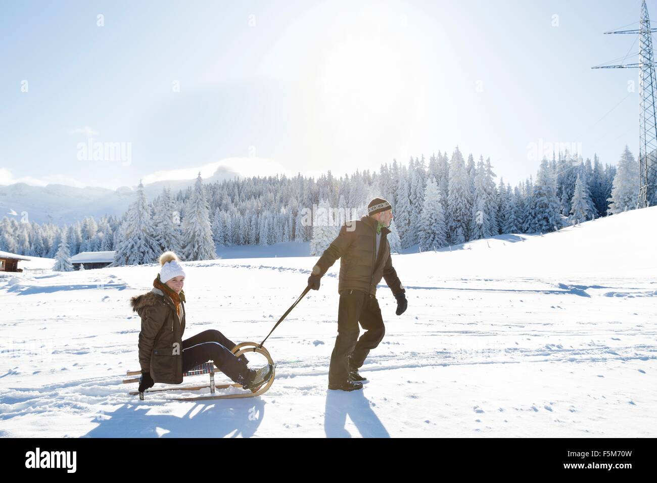 Seitenansicht des senior Mann zog senior Frau auf Schlitten, Sattelbergalm, Tirol, Österreich Stockfoto