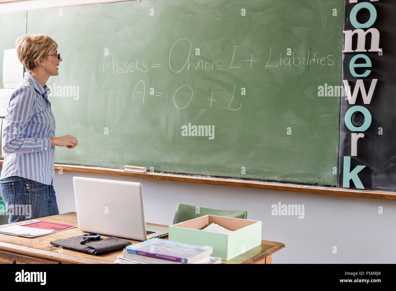 Lehrerin im Klassenzimmer, Blick auf Worte an Tafel Stockfoto