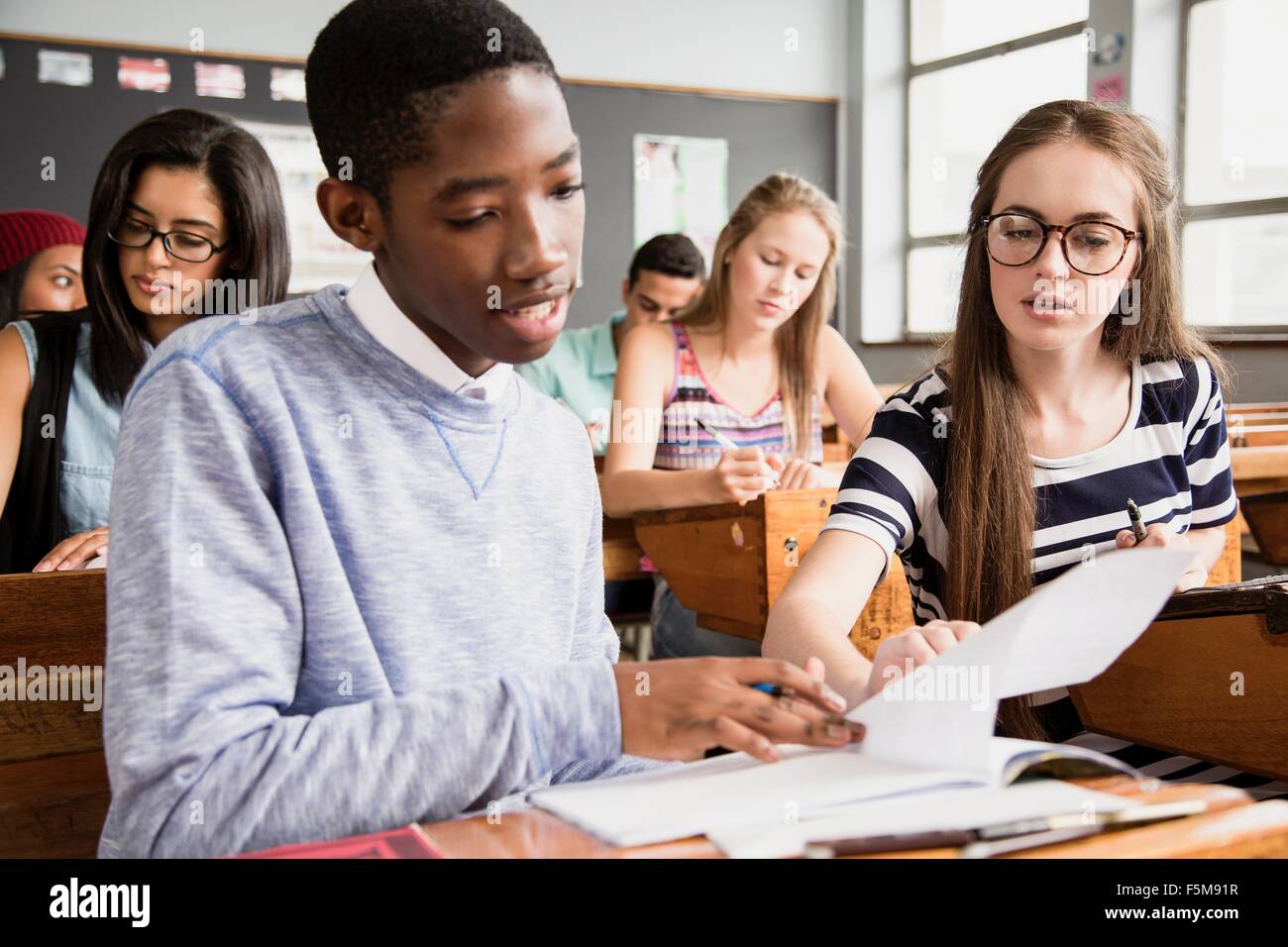 Zwei Studenten sitzen am Schreibtisch im Klassenzimmer, gegenseitig mit der Arbeit zu helfen Stockfoto