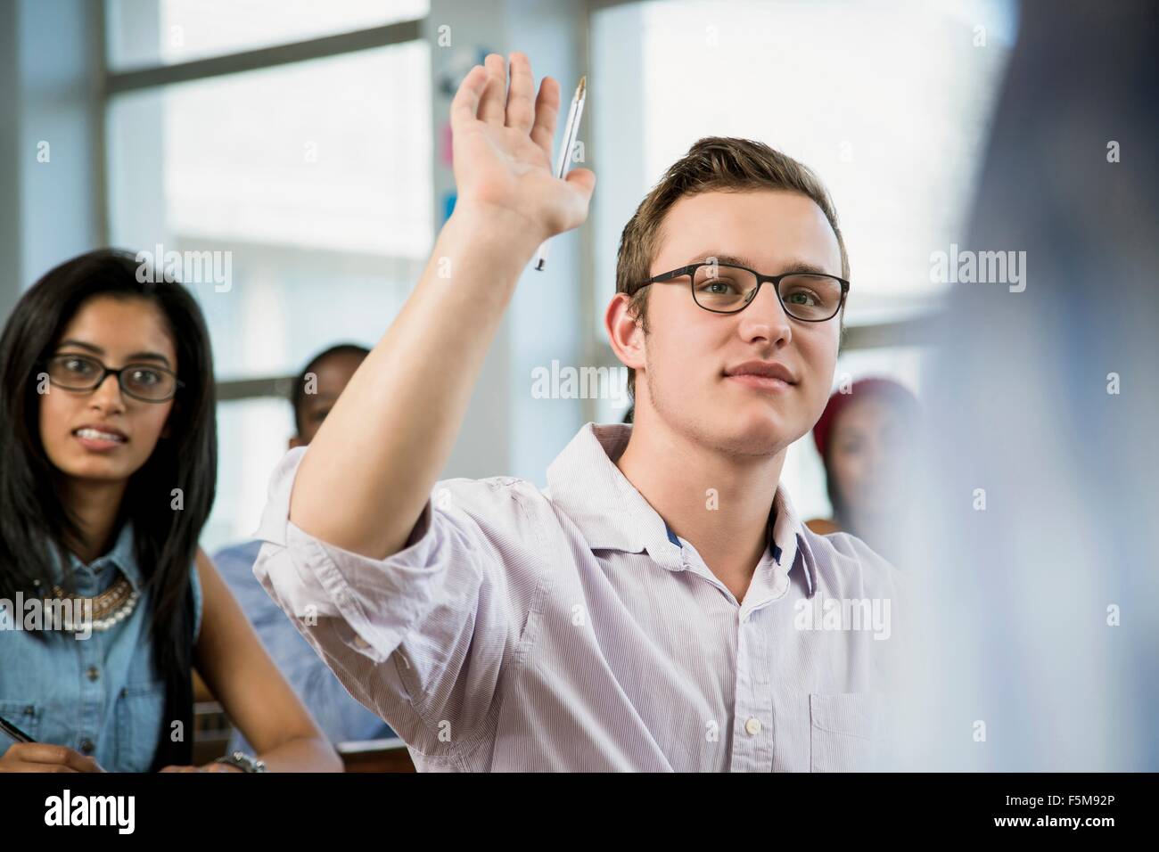 Männliche Schüler im Klassenzimmer, erhobener hand Stockfoto