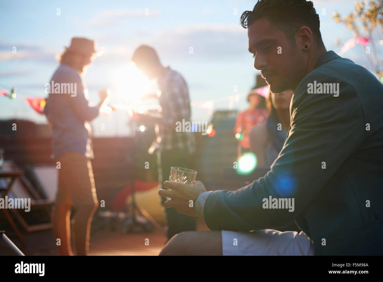 Mann sitzt allein mit Getränk am frühen Abend party Stockfoto