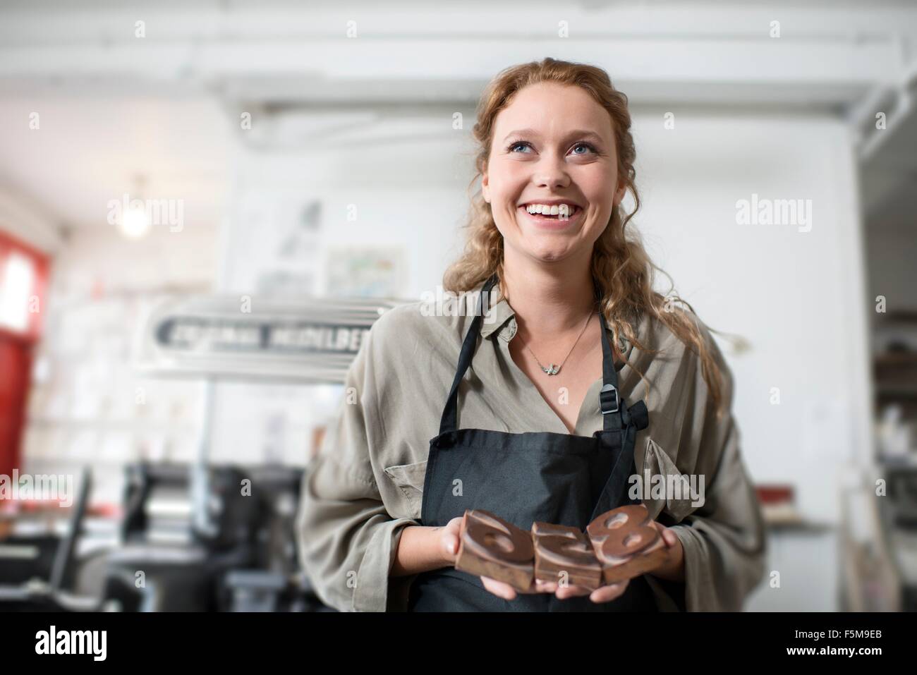 Junge Frau mit hölzernen Buchdruck in Druckwerkstatt Stockfoto