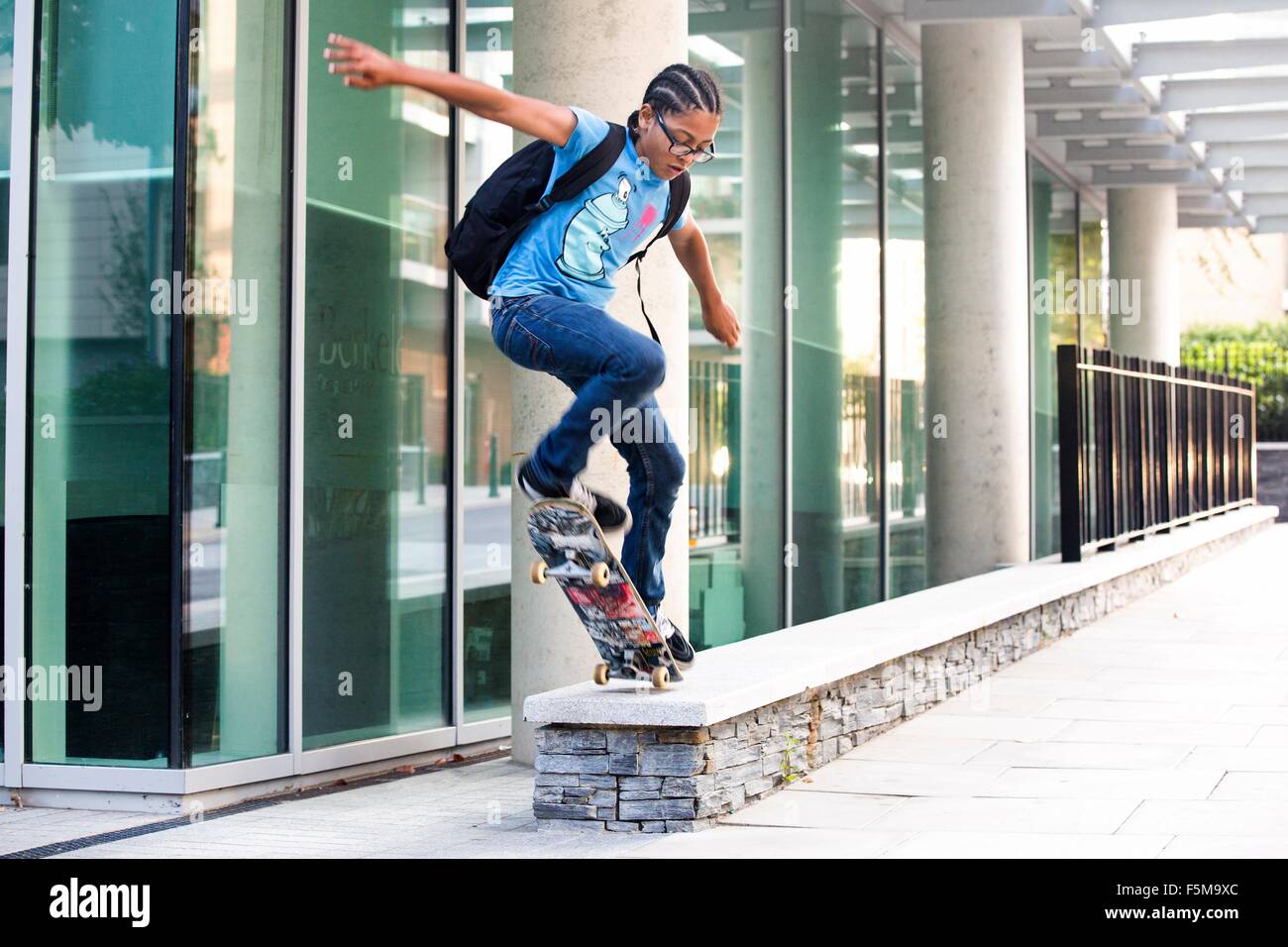 Junge Skateboard Trick Sprung auf städtischen Wand zu tun Stockfoto