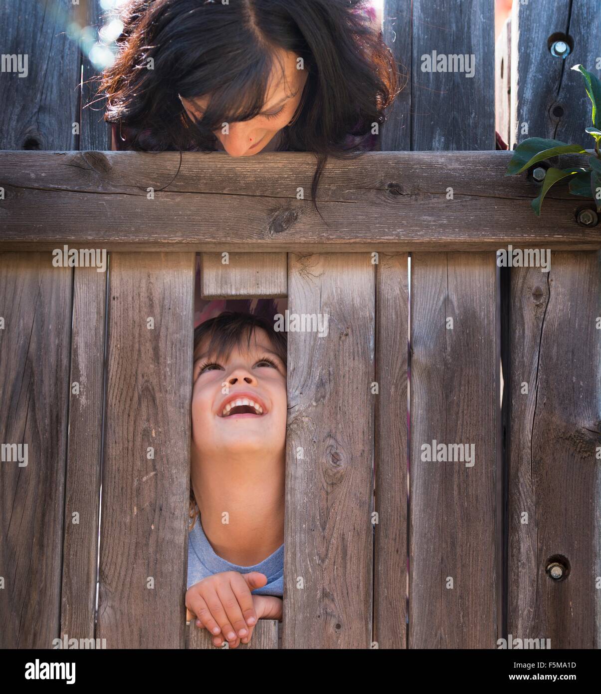 Mutter Sohn durch Loch im Zaun über betrachten Stockfoto