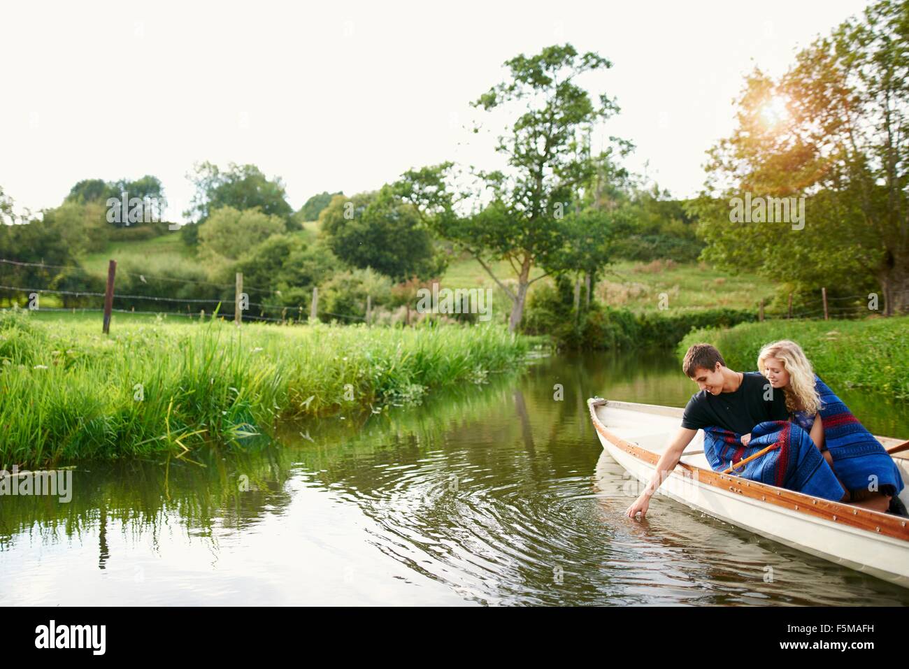 Junger Mann mit Freundin berühren Wasser vom Fluss Ruderboot Stockfoto