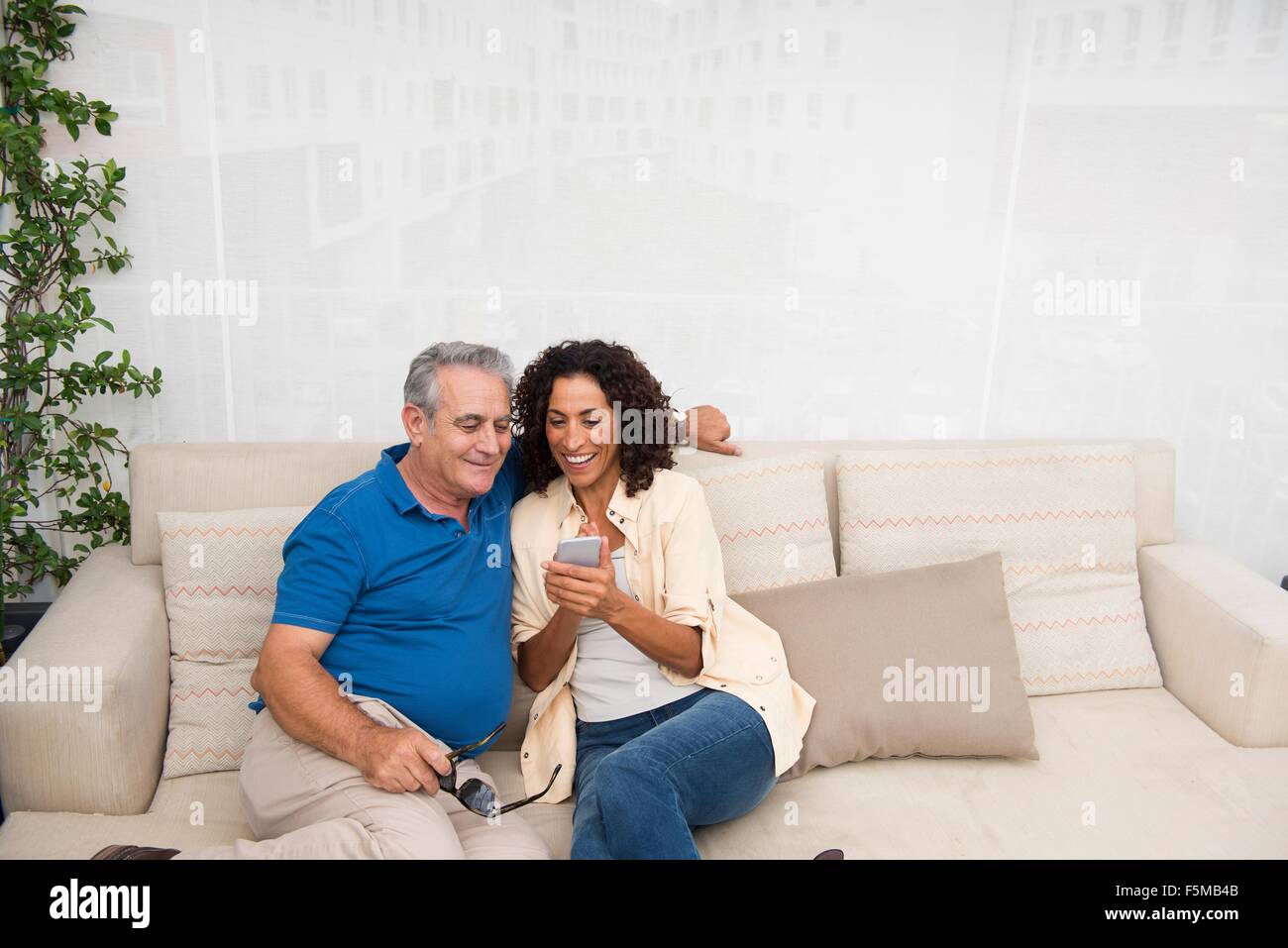 Ältere Mann und Frau lesen Smartphone Texte auf Terrasse sofa Stockfoto