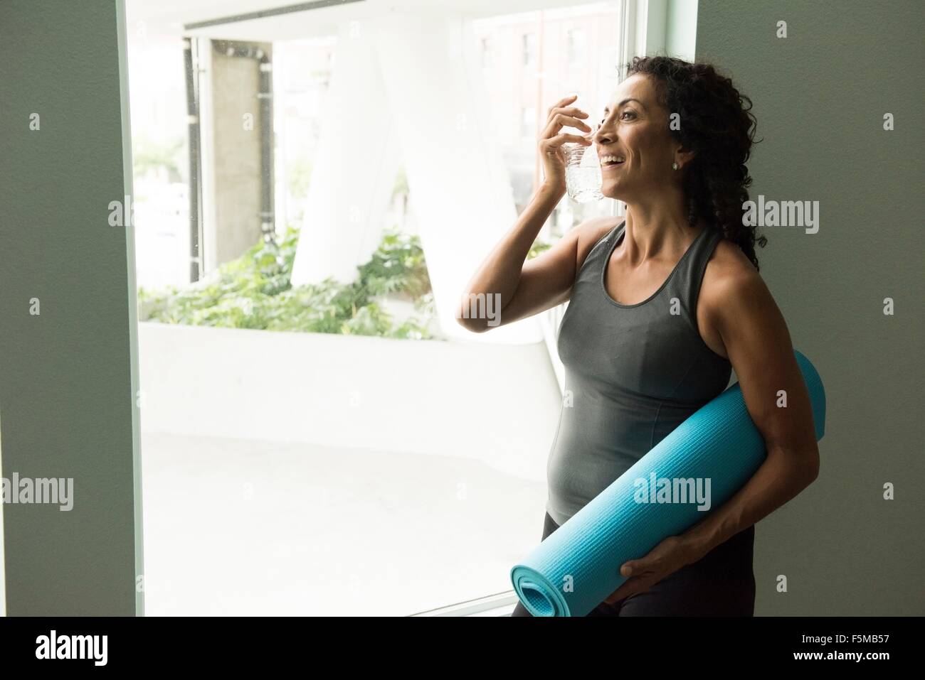 Reife Frau mit Yoga Matte Trinkwasser Stockfoto