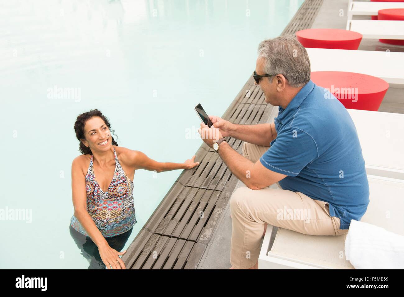 Senior woman fotografiert Frau mit Smartphone von am Pool Stockfoto