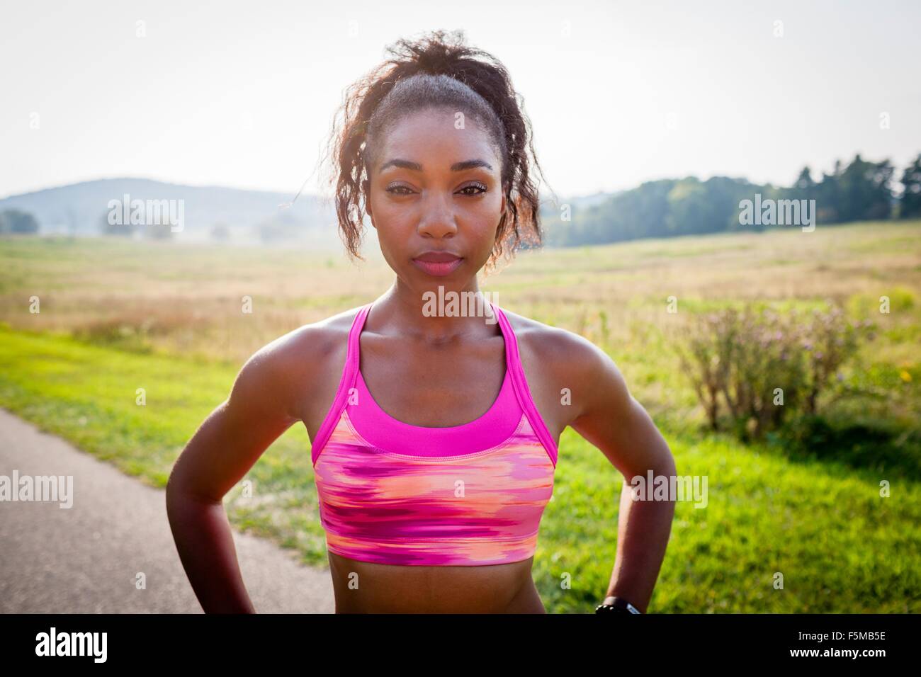 Porträt der jungen weiblichen Läufer mit Händen auf den Hüften im Naturpark Stockfoto