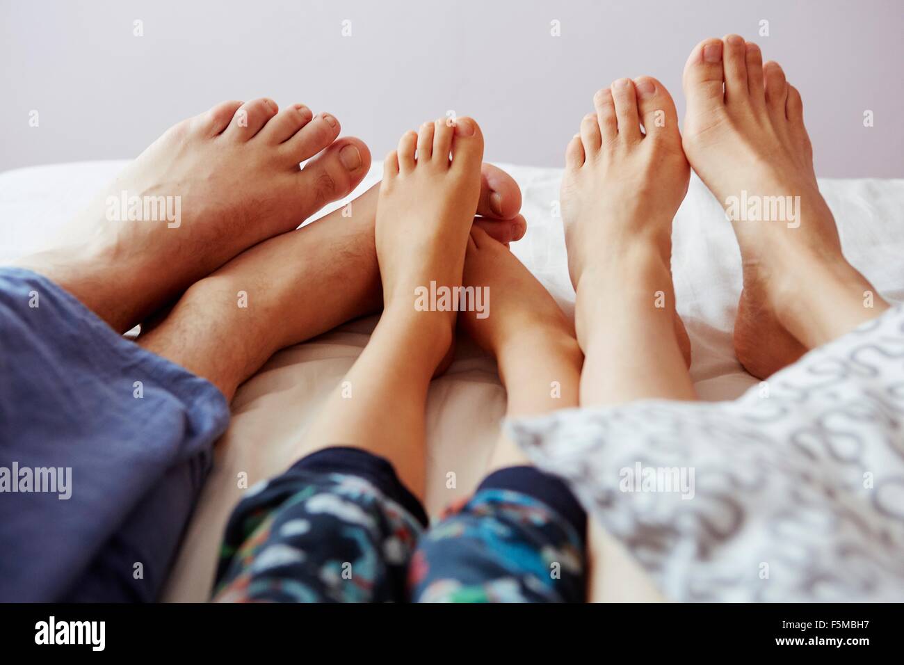 Beine und nackte Füße von Eltern und Sohn im Bett liegend Stockfotografie -  Alamy