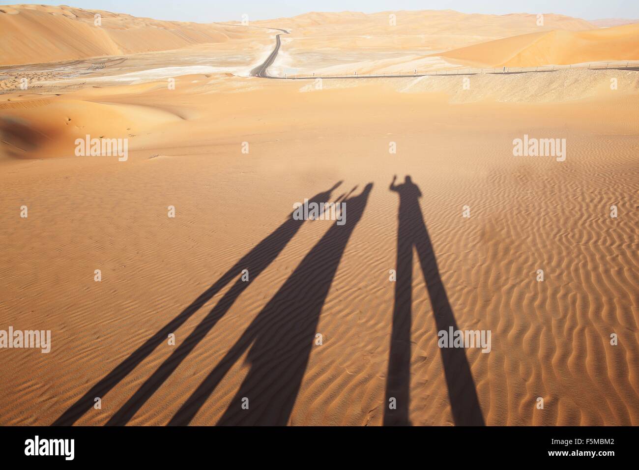 Schatten von drei Menschen auf Sand in der Wüste, Liwa-Oase, Abu Dhabi, Vereinigte Arabische Emirate Stockfoto