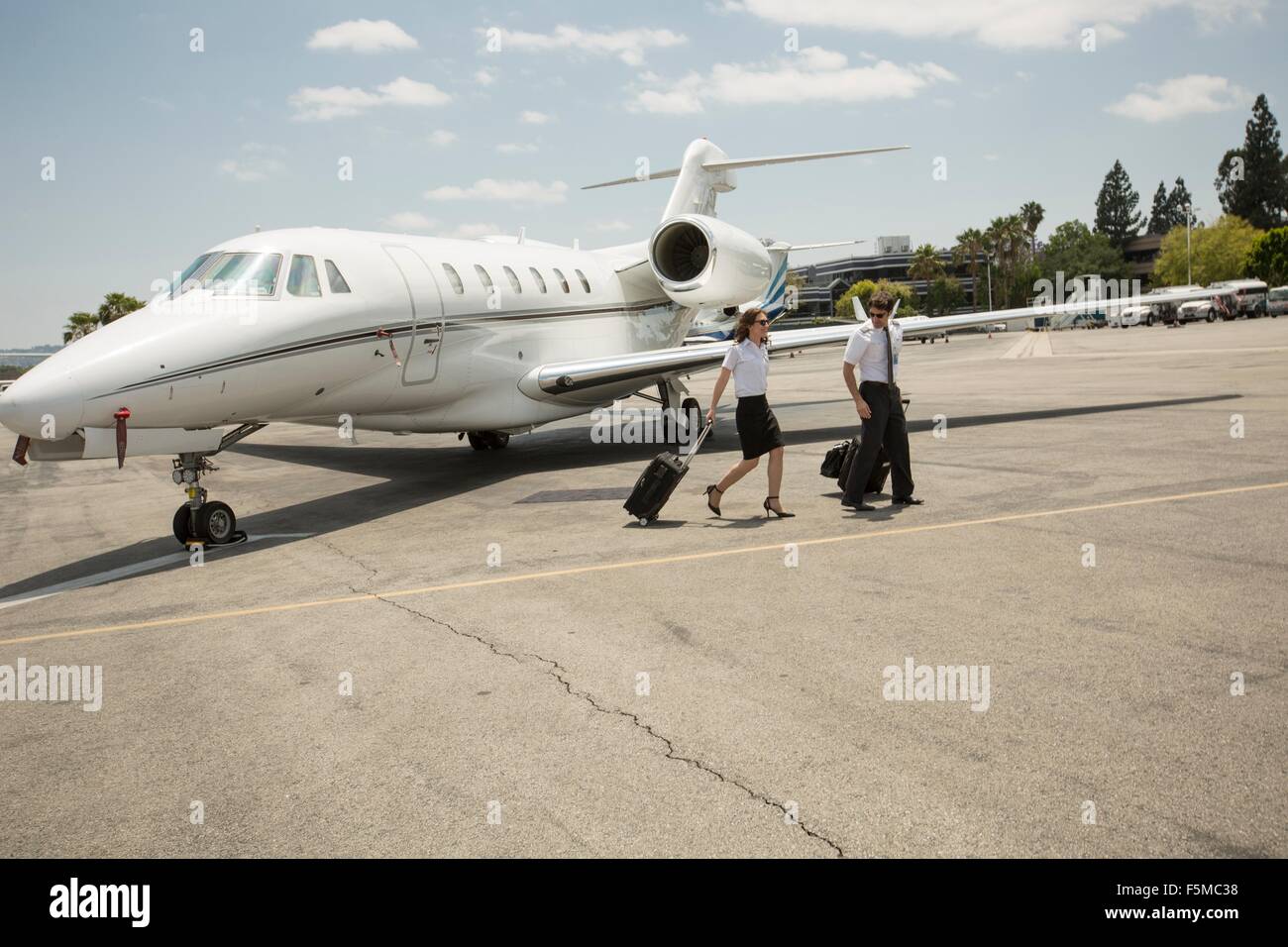 Männliche und weibliche private Jet-Piloten verlassen des Flugzeuges am Flughafen Stockfoto