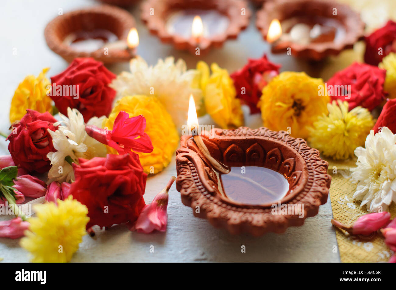 Diwali Diyas auf einem hölzernen Hintergrund mit festlichen Blumen und Lichter Stockfoto