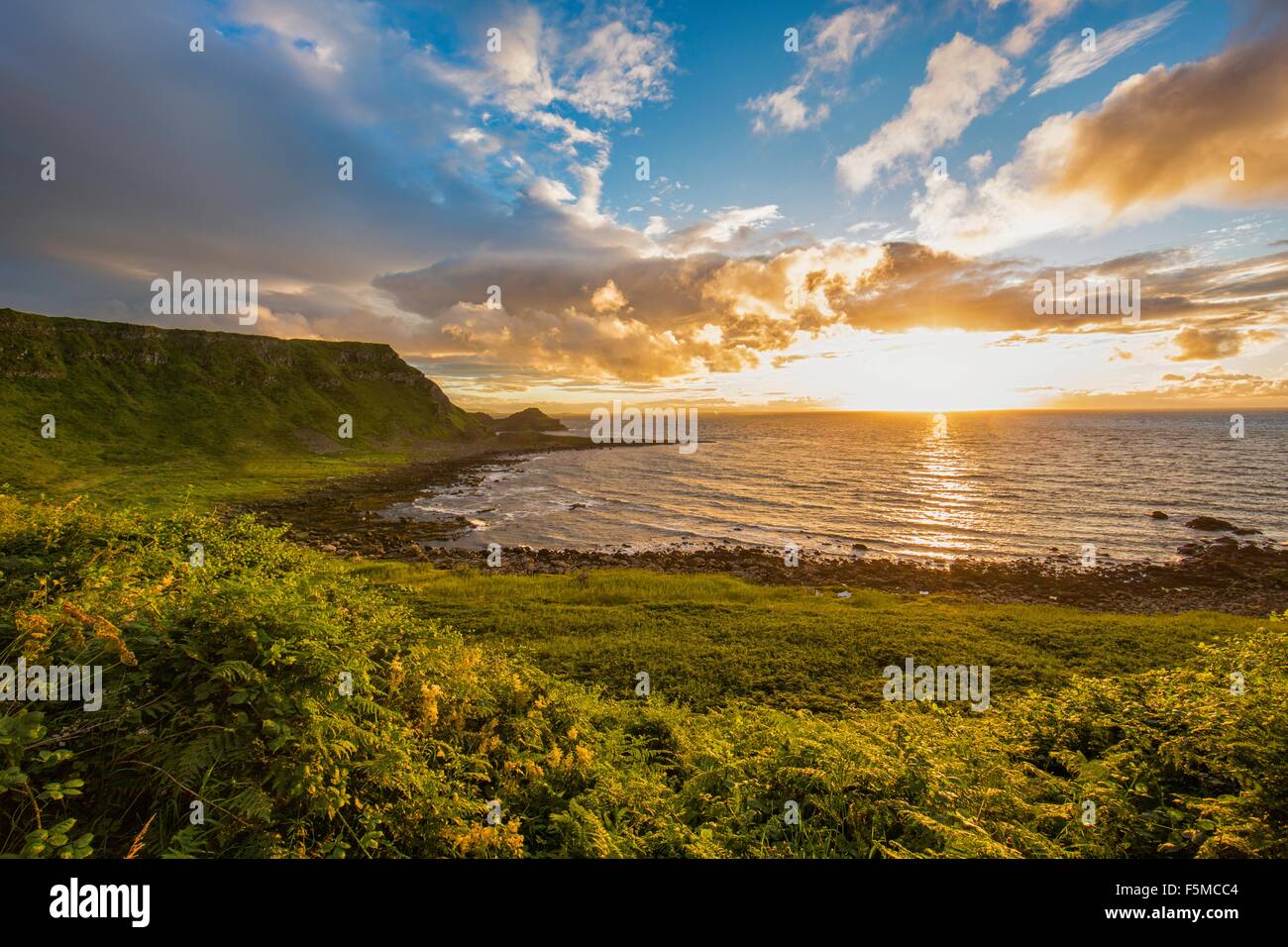 Die untergehende Sonne am Horizont über Ozean, Giants Causeway, Bushmills, County Antrim, Irland, UK Stockfoto