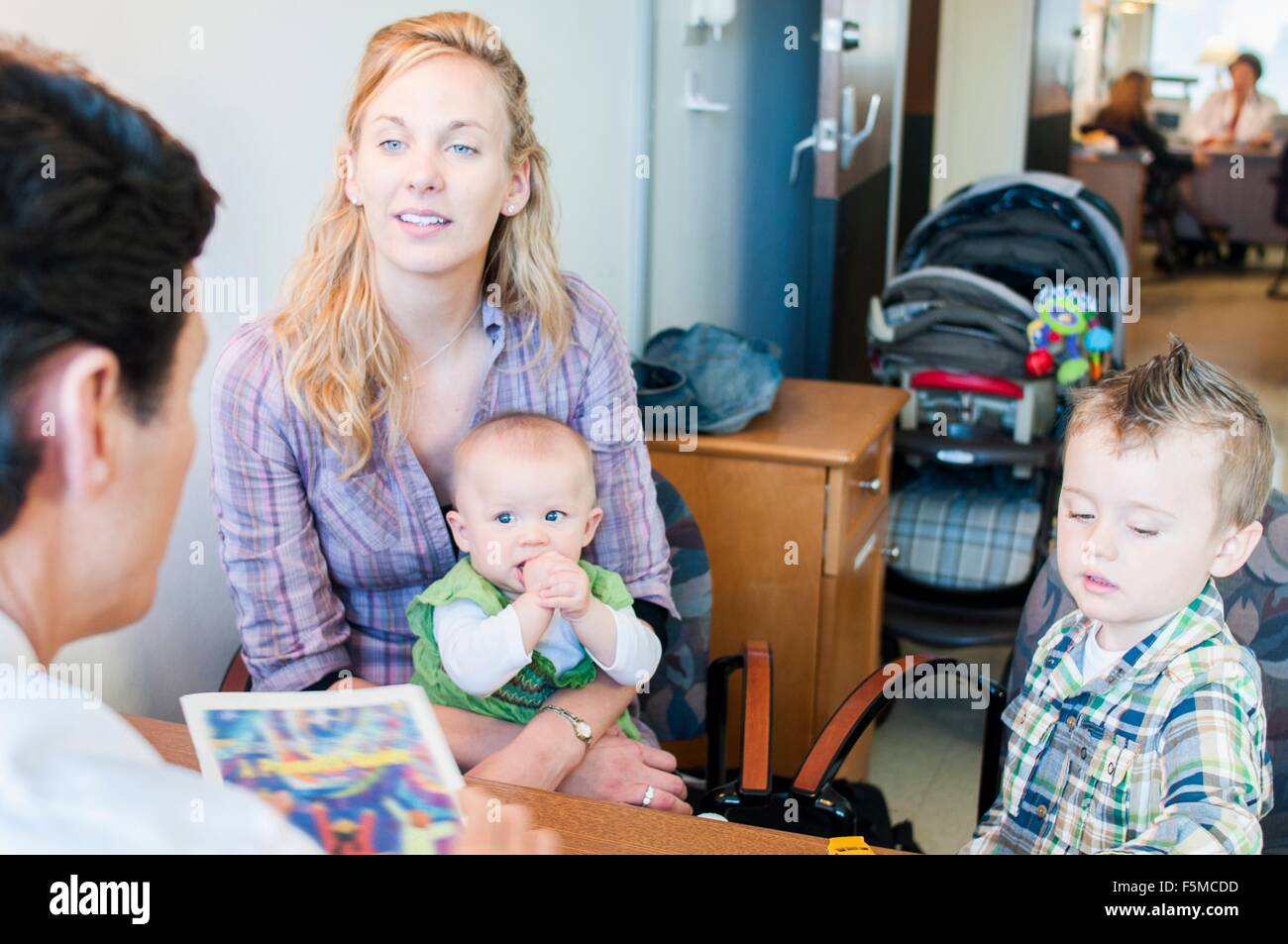 Mutter mit zwei Kindern, Gespräch mit Arzt sitzen Stockfoto