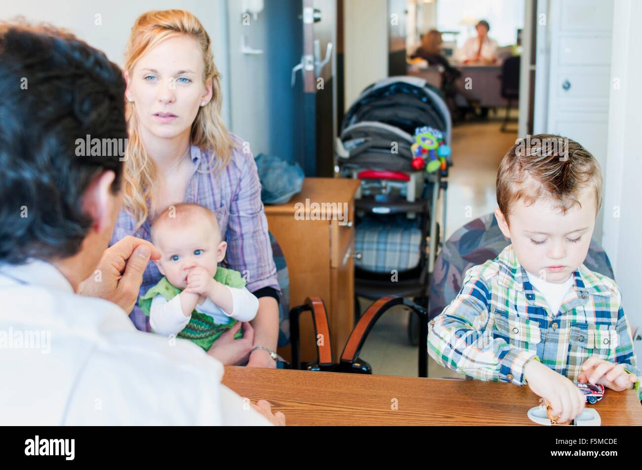 Mutter mit zwei Kindern, Gespräch mit Arzt sitzen Stockfoto