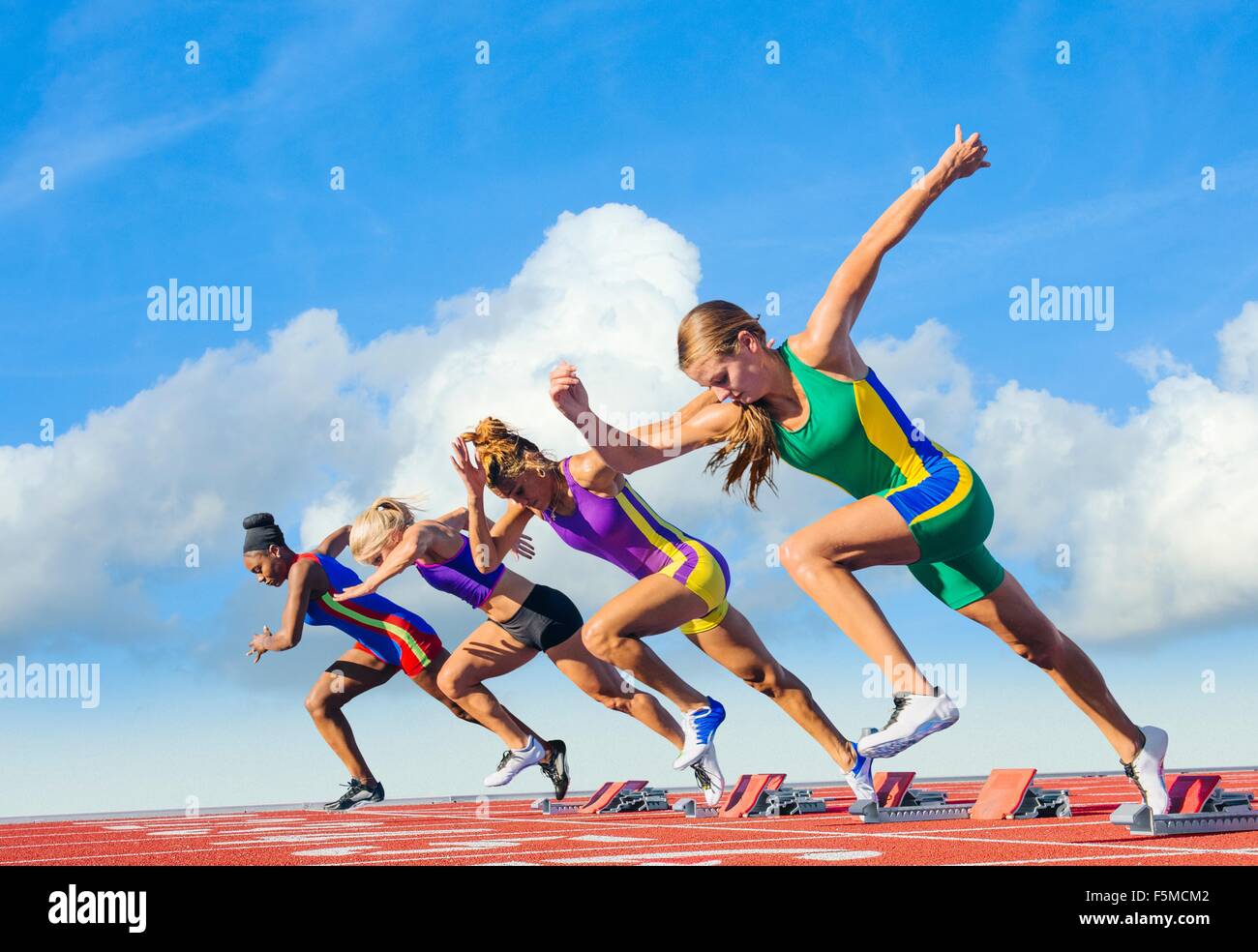 Vier weibliche Athleten auf Leichtathletikbahn, Start Stockfoto