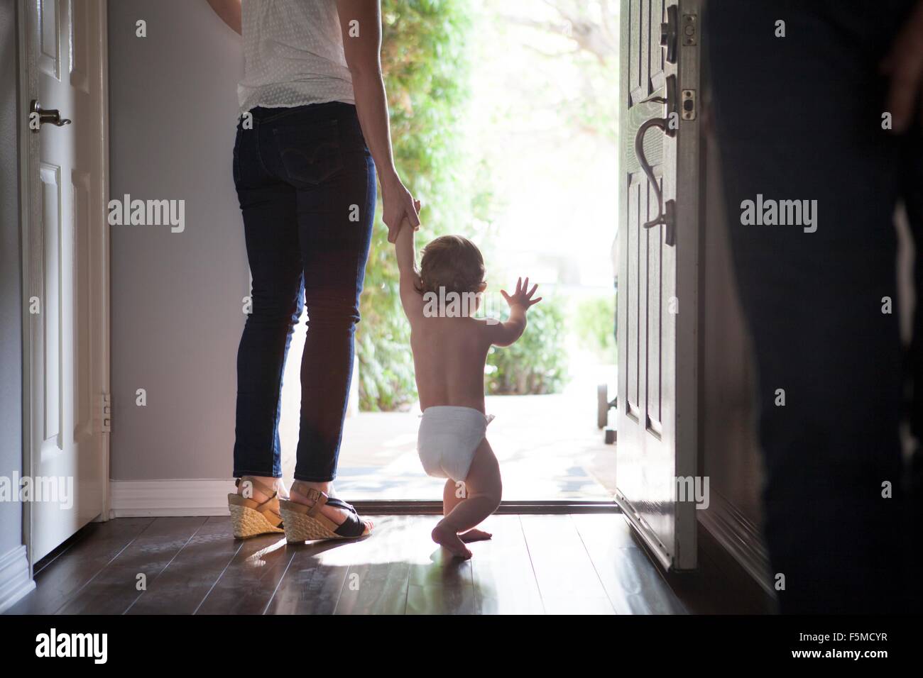 Rückansicht des Mutter Händchenhalten Baby jungen am offenen Haustür stehen Stockfoto