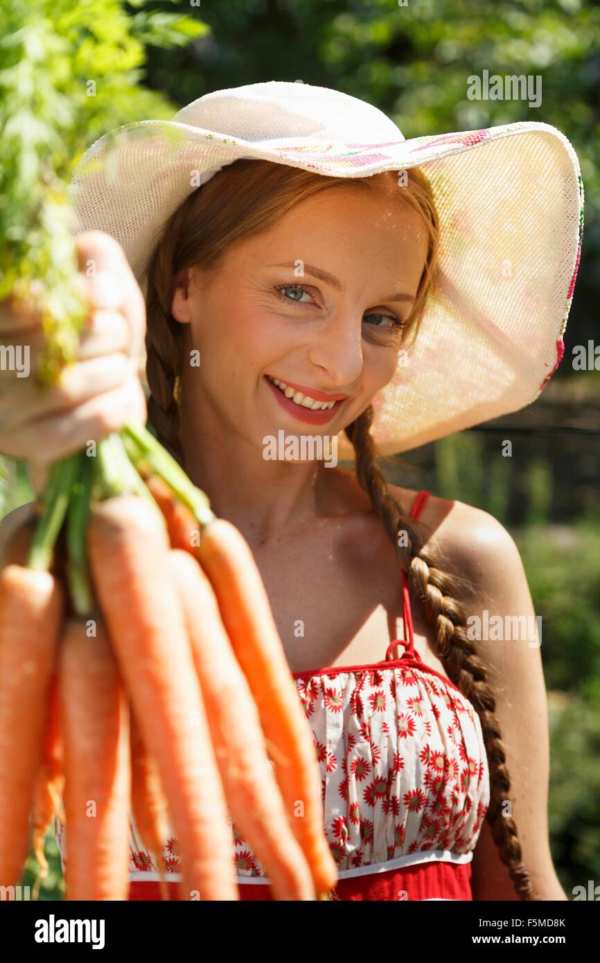 Porträt von Mitte Erwachsene Frau im Garten, halten Bund Karotten Stockfoto