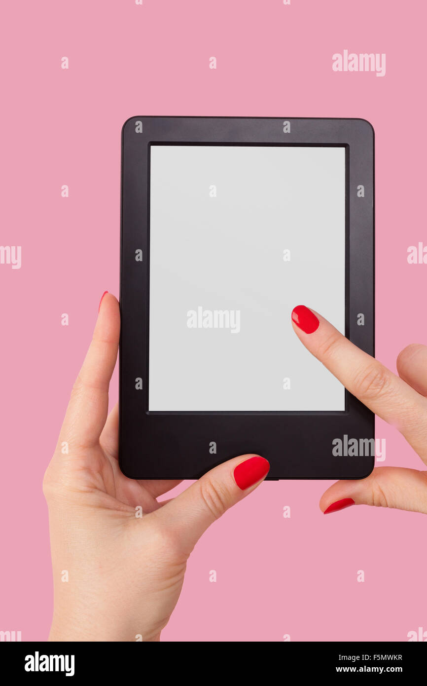 Weibliche Hand hält e-Reader auf rosa Hintergrund isoliert. Lesung, Bildung und Lernkonzept. Stockfoto