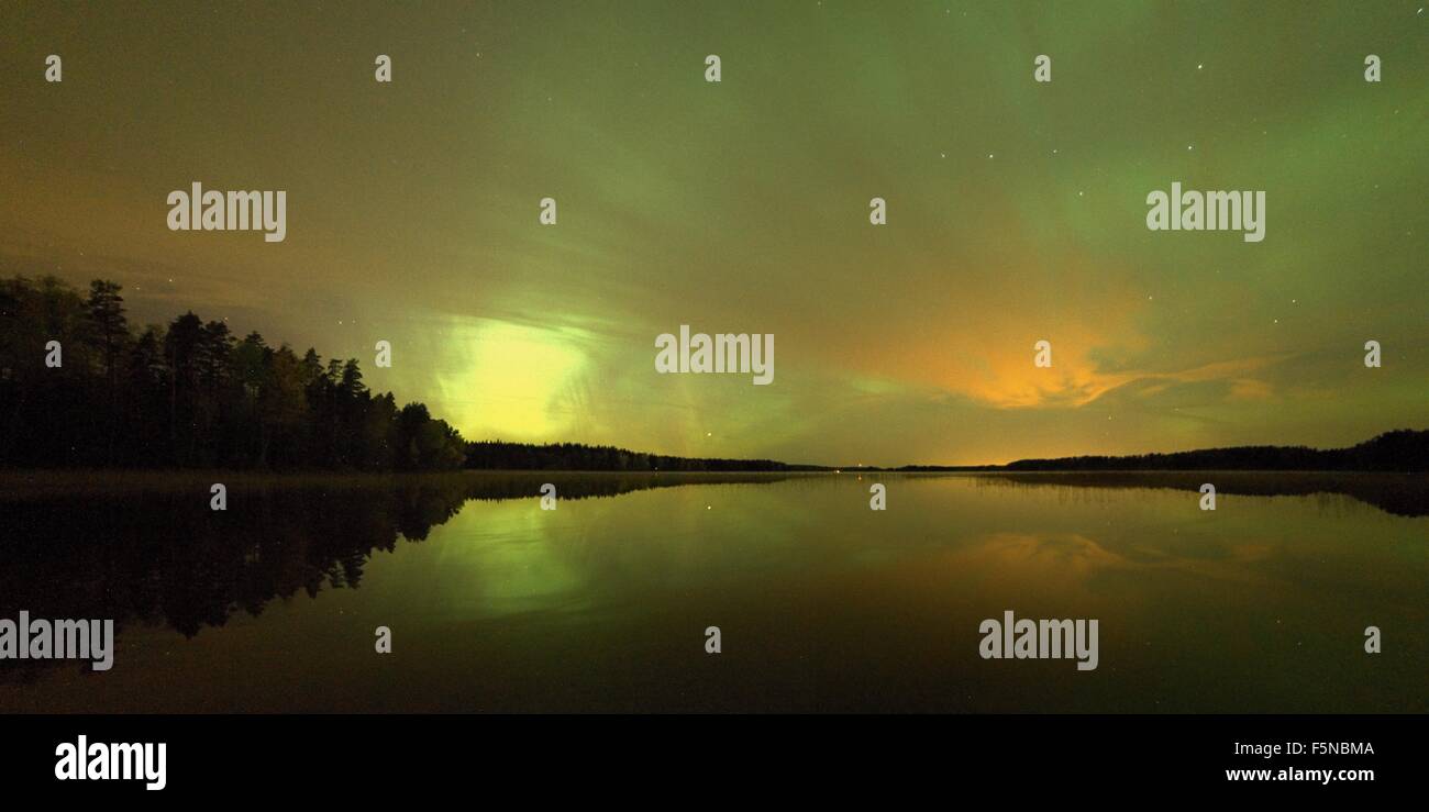 Nordlichter (Aurora Borealis) am Nachthimmel über einem friedlichen See in Finnland. Einige Nacht-Wolken am Himmel Andsymmetric r Stockfoto