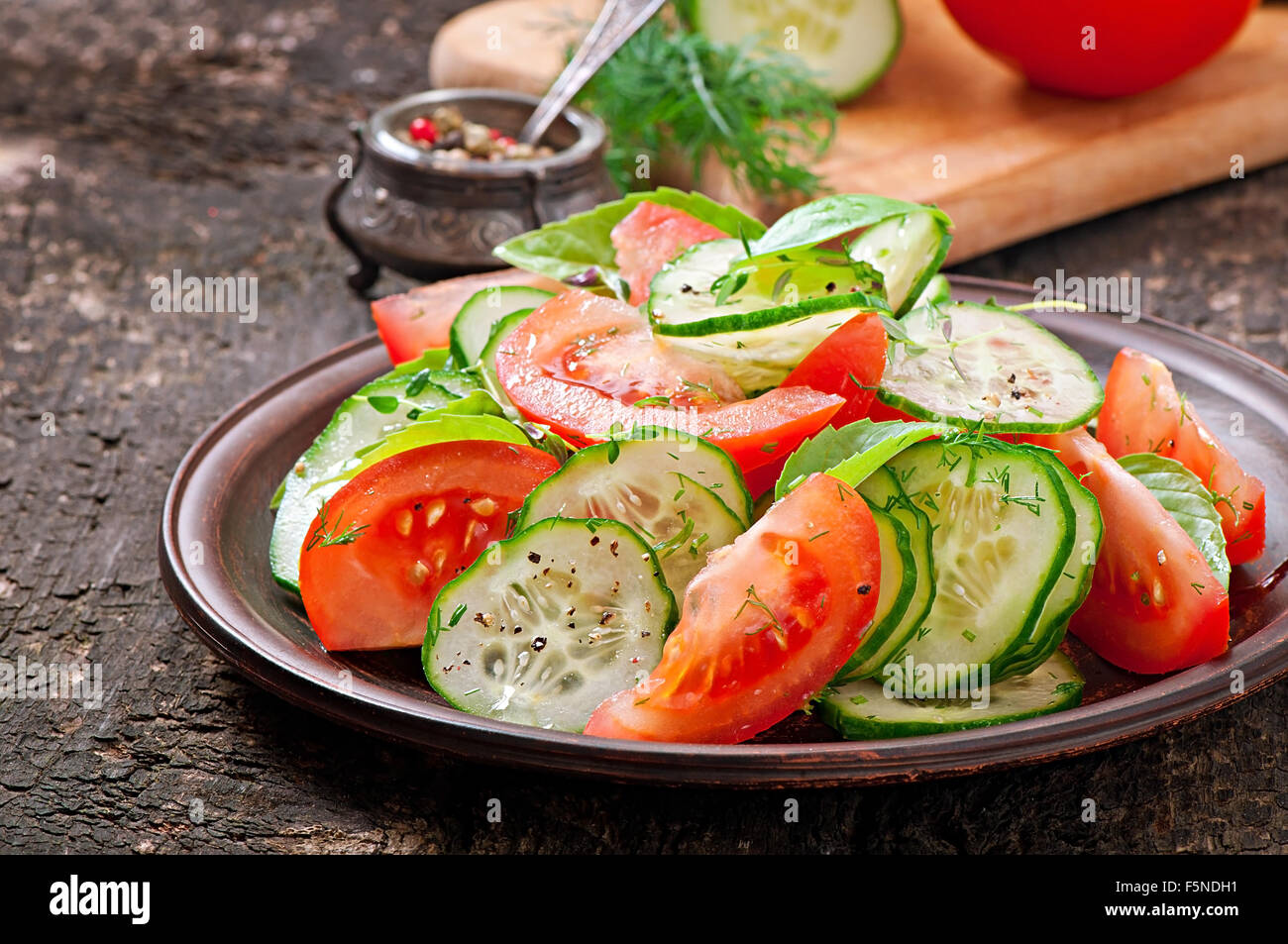 Tomaten und Gurken Salat mit schwarzem Pfeffer und Basilikum Stockfoto