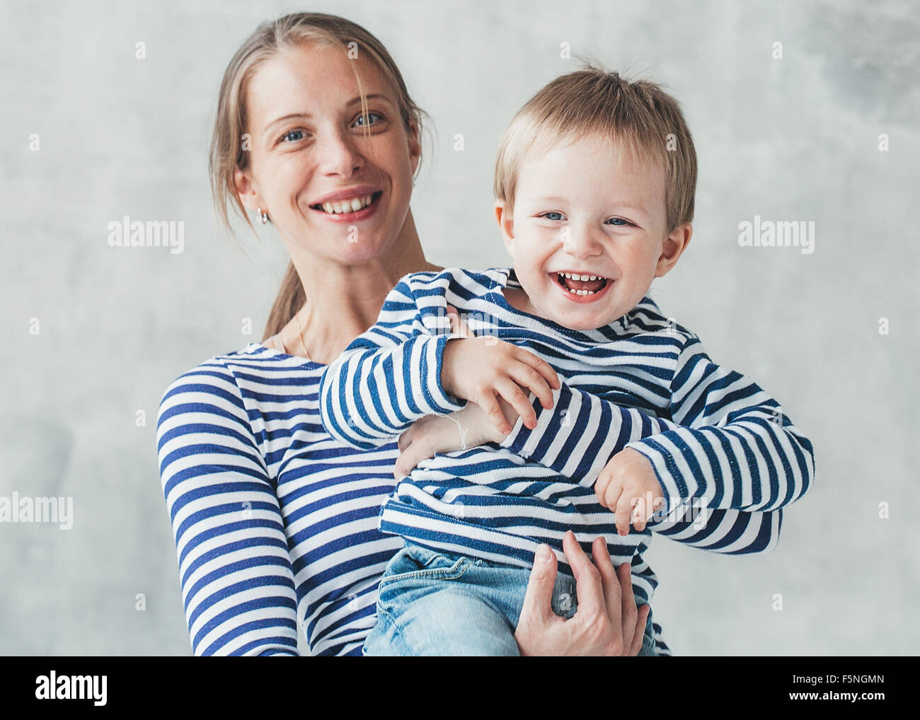Familie Mutter mit jungen Sohn im gleichen gestreift modischer Kleidung auf graue Wand Hintergrund Studioportrait Stockfoto