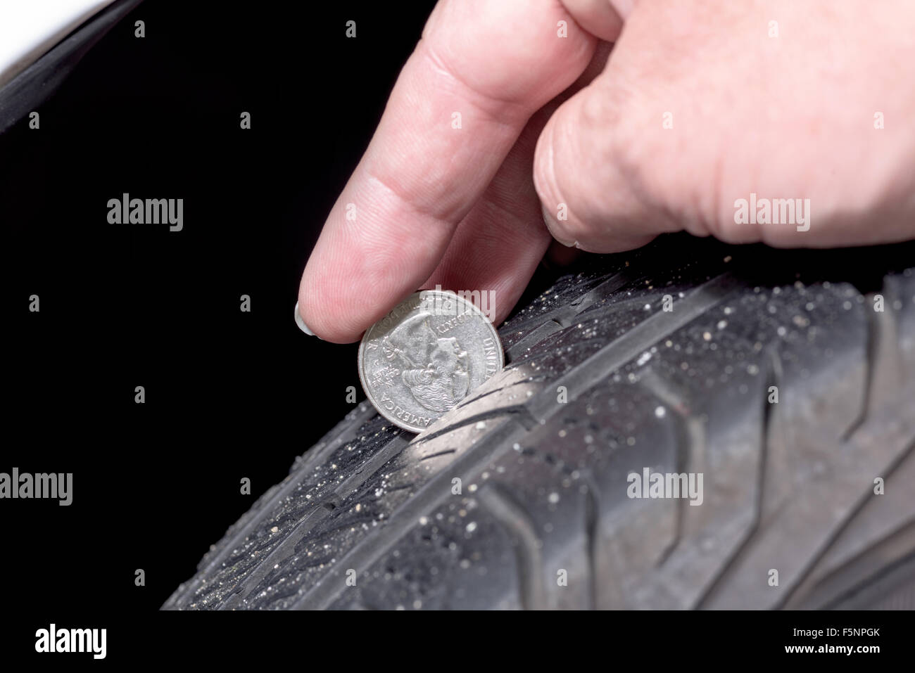 Die Tiefe überprüfen, ob Reifen Verschleiß mit einem Viertel Lauffläche Stockfoto