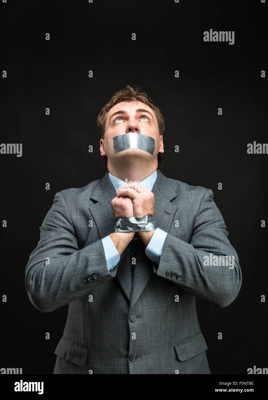 Mann mit Mund und Händen fallenden Klebeband verhindert Rede, isoliert auf schwarz Stockfoto
