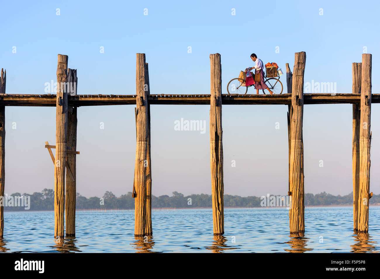 Ein Radfahrer schiebt sein Fahrrad über die U Bein Brücke über Taungthaman-See in Mandalay, Myanmar. Stockfoto