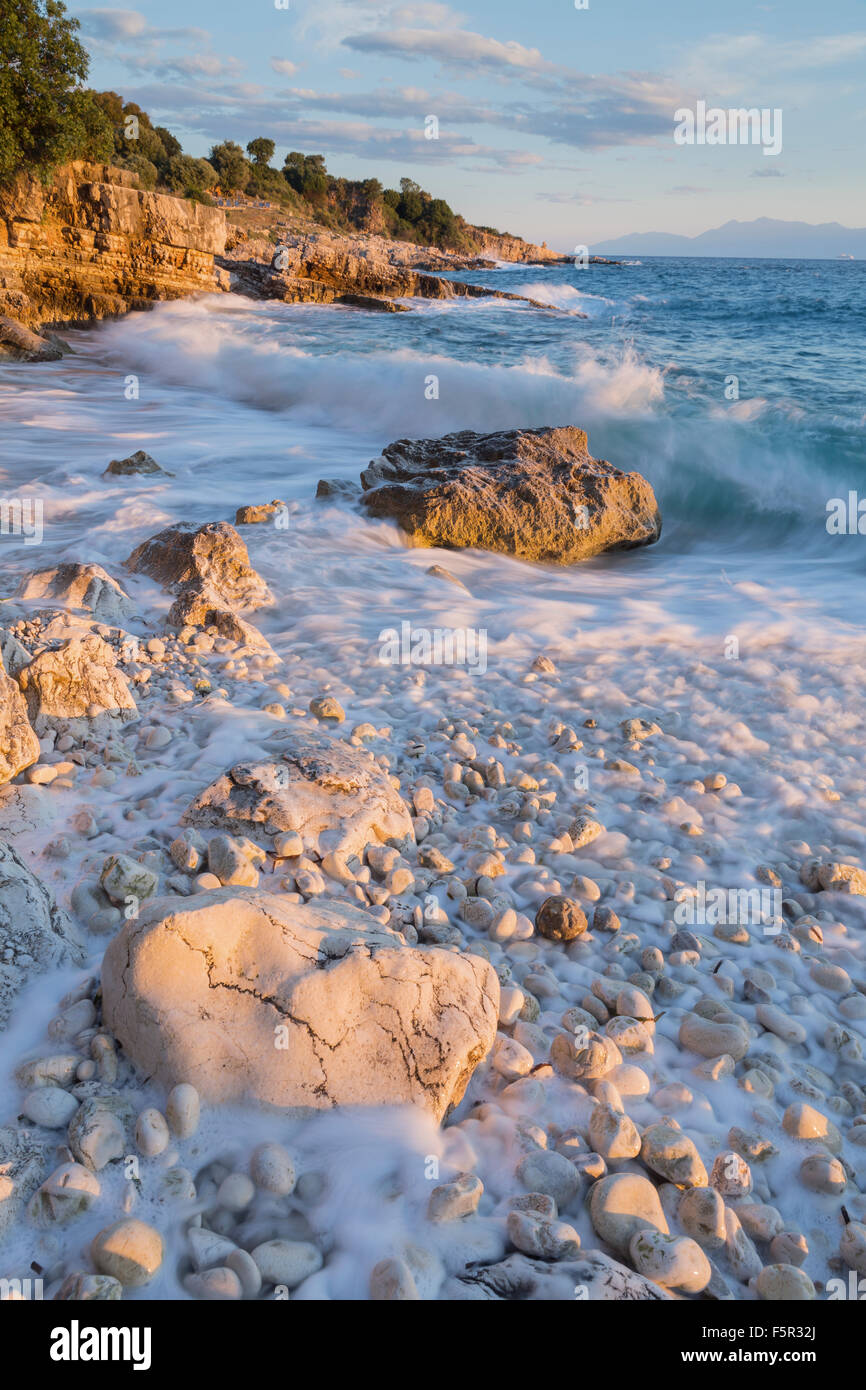 Die Kieselsteine und Felsen auf Bataria Strand, Kassiopi, Korfu Leuchten mit dem Stong orange Licht des Sonnenaufgangs. Stockfoto