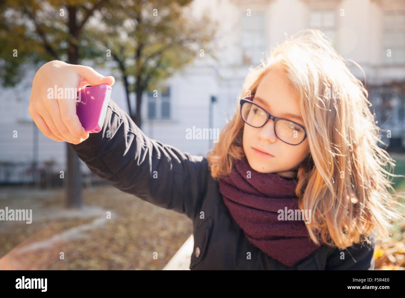 Schöne kaukasischen blonde Teenager-Mädchen nehmen Foto auf ihrem Smartphone im herbstlichen Park, selektiven Fokus auf der Seite mit Telefon, shal Stockfoto
