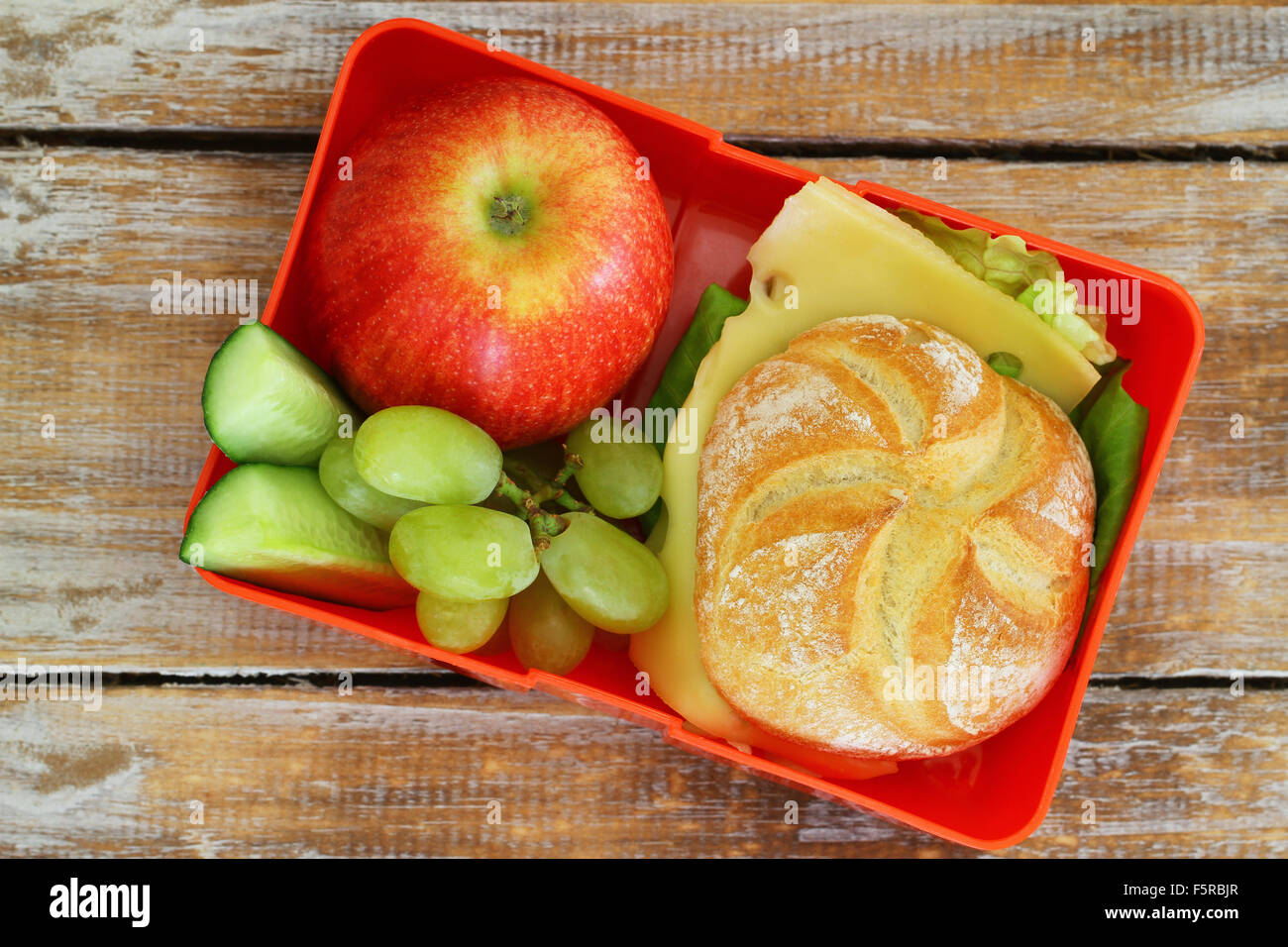 Schule-Lunch-Box mit Käse Roll, roten Apfel und Trauben Stockfoto