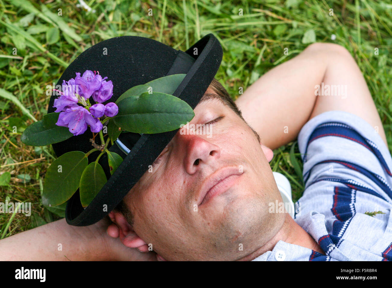 Ein schlafender Mann mit Hut nimmt Teil am traditionellen Setzgras auf der Wiese Stockfoto