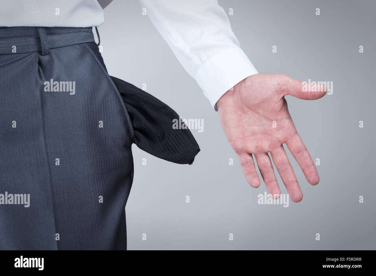 Geschäftsmann herausziehen leeren Taschen über grauen Hintergrund Stockfoto