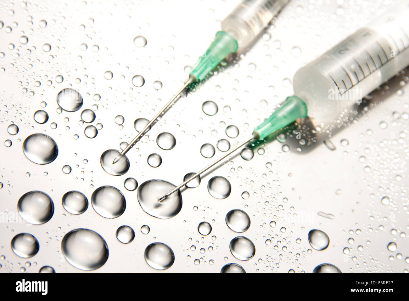 Zwei medizinische Spritzen und Wassertropfen Stockfoto