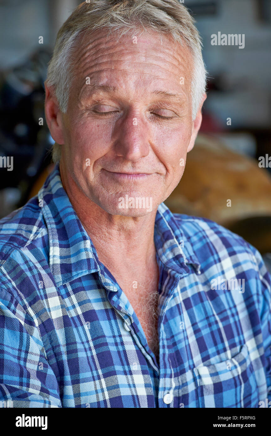 Porträt von einem reifen Alter Mann mit seinen Augen geschlossen sein glückliche Leben in seinem Stall zu betrachten Stockfoto