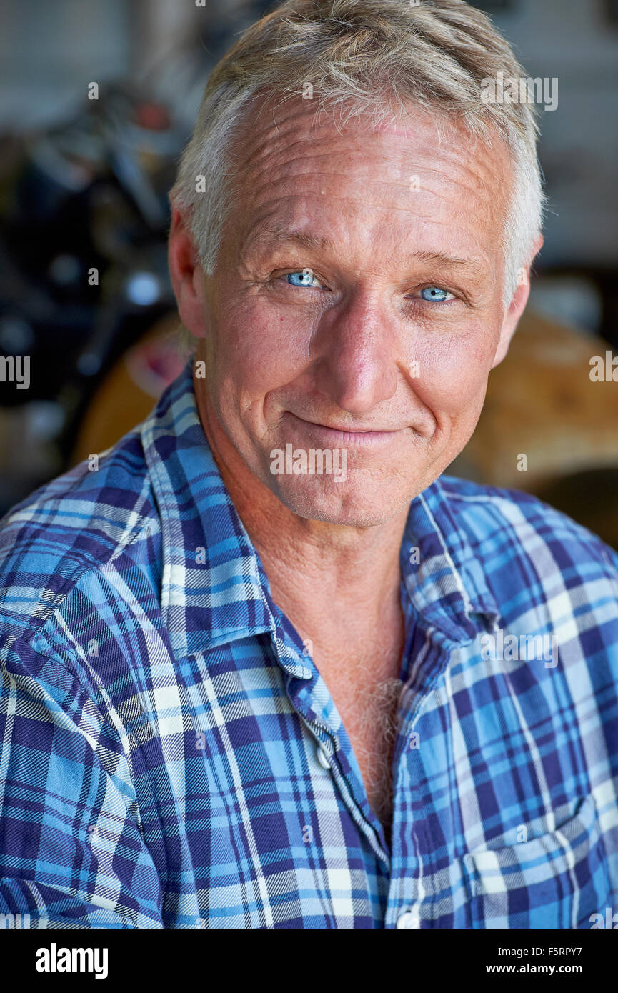 Porträt von einem reifen Alter Mann mit seinem Motorrad im Hintergrund Stockfoto