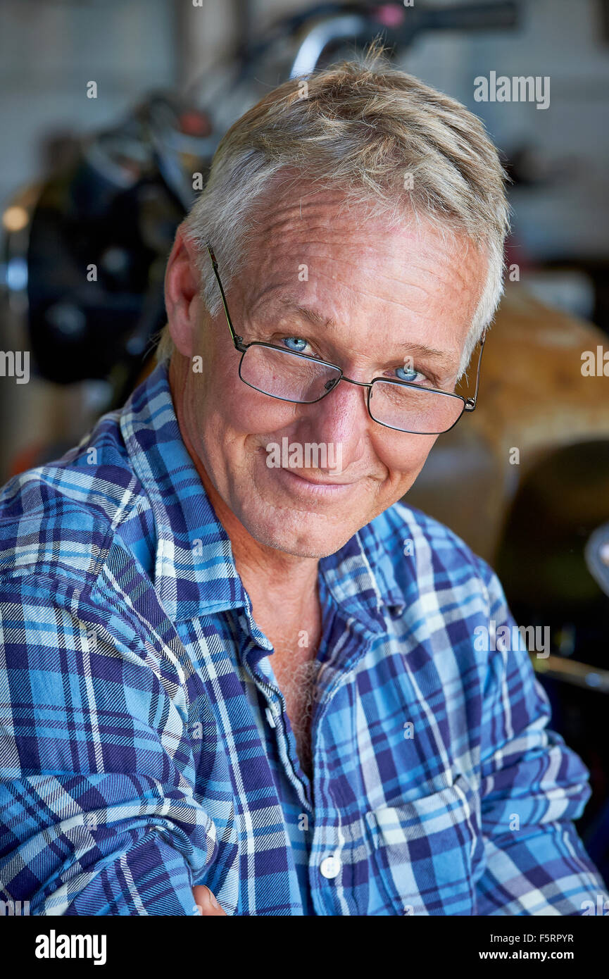 Porträt von einem reifen Alter Mann mit seinem Motorrad im Hintergrund Stockfoto