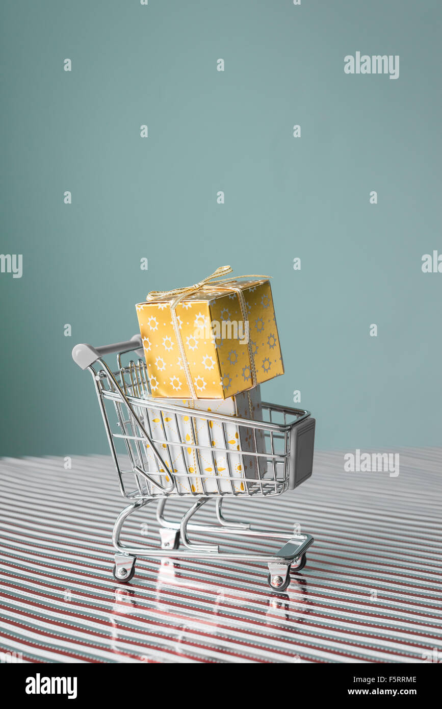 Mini Trolley mit Weihnachtsgeschenk auf Xmas Streifen auf blauem Grund Stockfoto