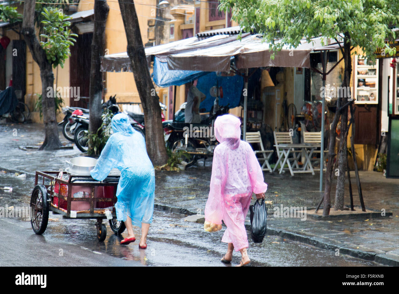 Hoi an eine alte Stadt in Vietnam. Nasse Saison und schwere Regenfälle in der Stadt. Menschen vor Ort tragen Kunststoff Macs zu trocken zu halten Stockfoto