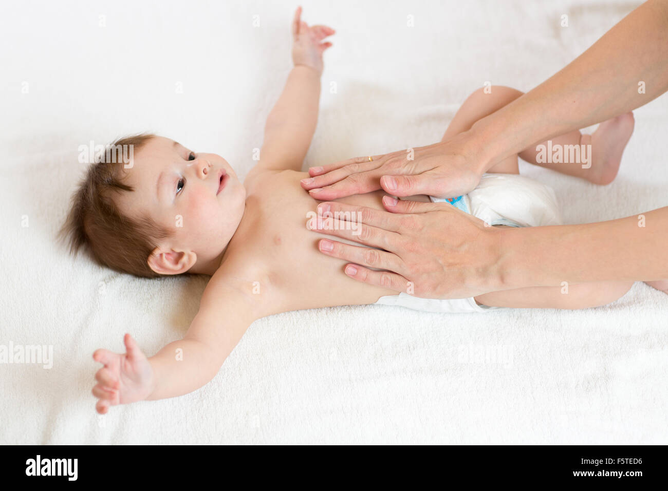 Baby-Massage. Mutter Baby Bauch massieren Stockfoto