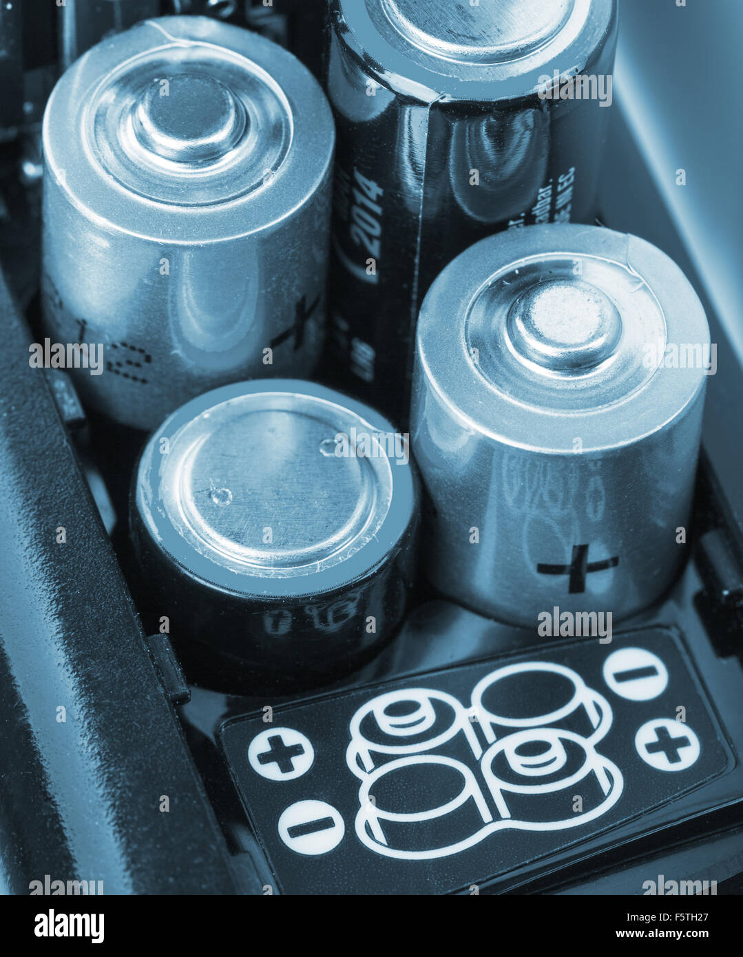 Laden von Batterien in ein elektronisches Gerät. In blau getönt Stockfoto