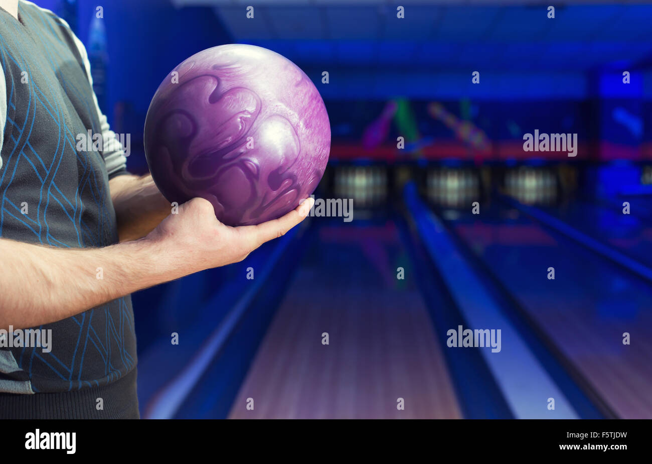 Mann mit Ball gegen Kegelbahn Stockfoto