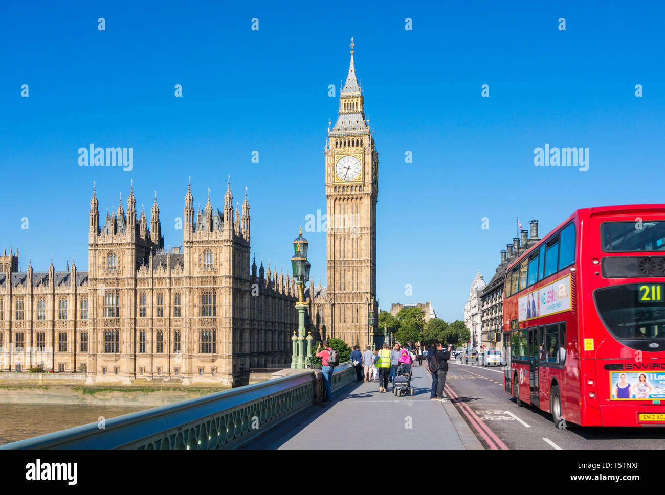 Roter Bus vorbei an Big Ben Houses of Parliament und Westminster Brücke über den Fluss Themse Stadt von London England GB UK Europe Stockfoto