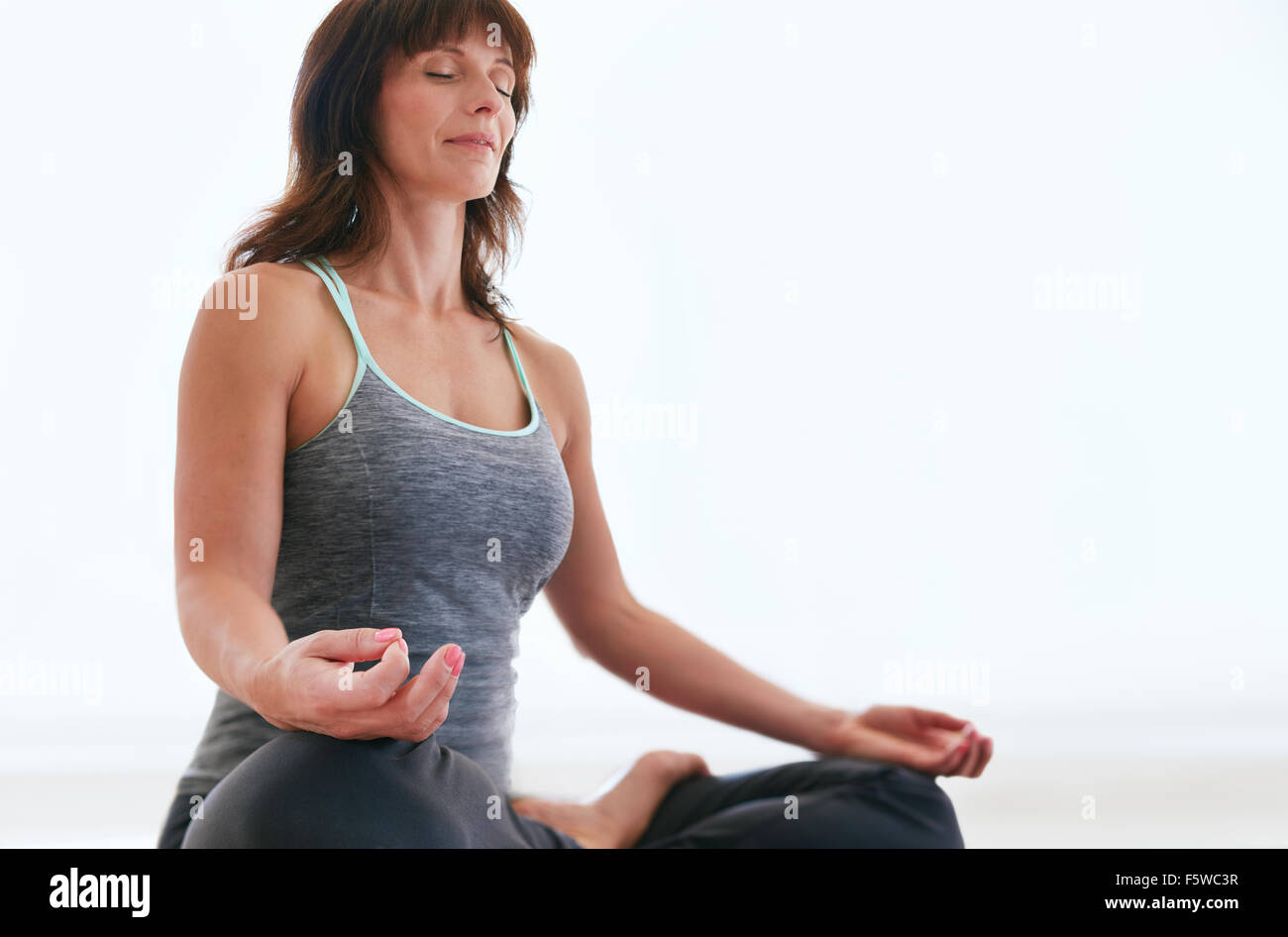 Porträt von Fit Frau im Lotus Pose meditieren. Weibliche Trainer Padmasana in Turnhalle zu üben. Stockfoto